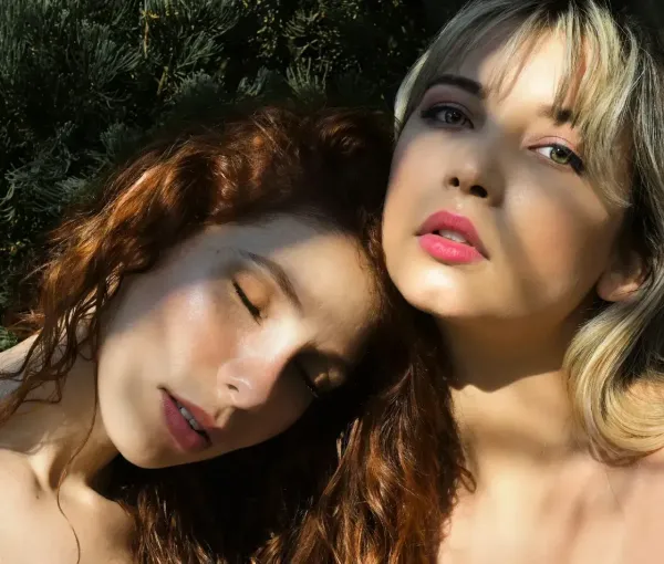 Portrait de deux femmes avec maquillage naturel et lumière douce, posant en extérieur